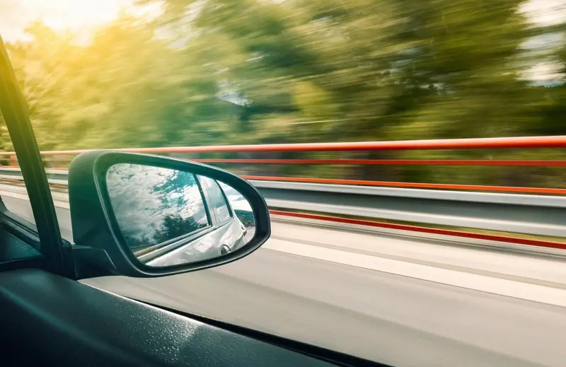 A car driving on the highway with trees in the background.